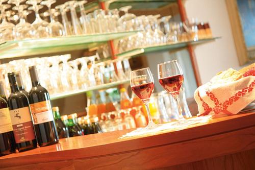 two glasses of wine sitting on a bar with wine bottles at Pension zum Burggräfler in Schenna