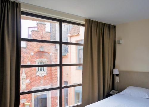 a bedroom with a window with a view of a building at Hotel 't Putje in Bruges
