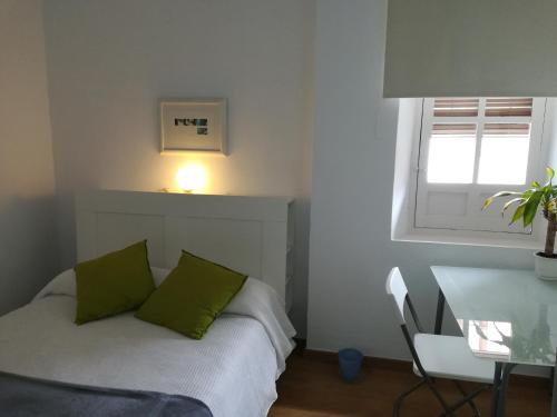 Un dormitorio con una cama con almohadas verdes y una mesa. en Nice apartment in the center of Granada, en Granada
