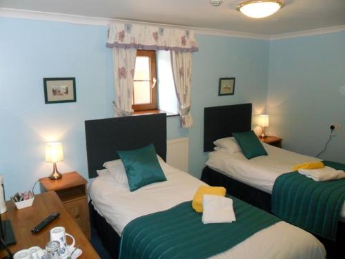 a room with two beds and a table with two lamps at Stag Coach House in Carmel
