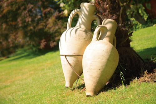 three white vases sitting next to a tree at Pension zum Burggräfler in Schenna