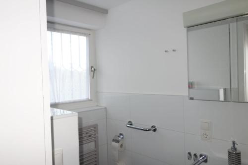 Baño blanco con lavabo y espejo en Apartment Werner, en Niederbachem