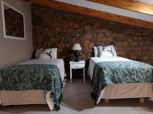 two beds in a room with a stone wall at Arend Cottage in Nelspruit