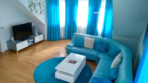 フロイデンシュタットにあるSchwarzwald Appartmentのリビングルーム(青いソファ、テレビ付)