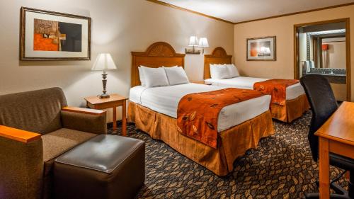 a hotel room with two beds and a chair at SureStay by Best Western Kansas City Country Inn North in Kansas City