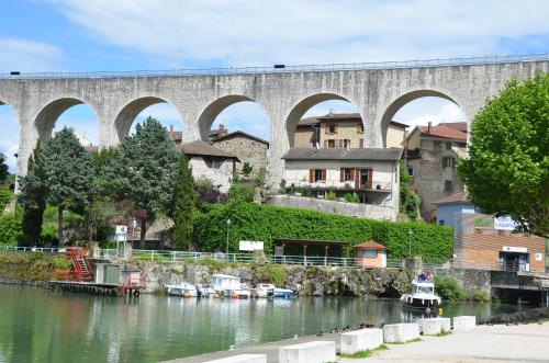 a bridge over a river with boats in the water at La Bastide de Fontaille in Saint-Félicien
