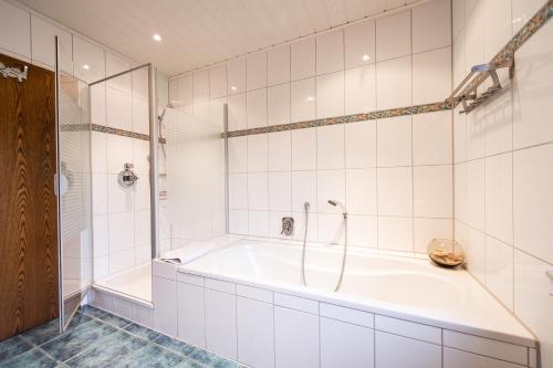 a white bathroom with a tub and a shower at Ferienwohnung Virginija in Ditscheid