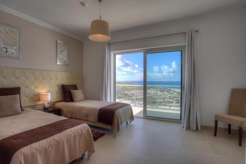 a bedroom with two beds and a view of the ocean at The Beachfront - Praia D'El Rey Golf & Beach Resort in Casal da Lagoa Seca