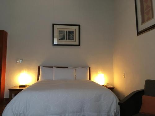 a bedroom with a white bed and two lamps at Quinta Luna in Cholula