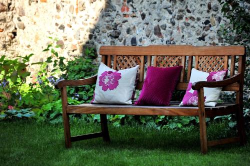 a wooden bench with four pillows on the grass at Renaissancehotel Raffelsberger Hof B&B in Weissenkirchen in der Wachau