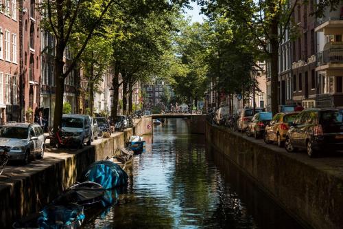 a canal with cars parked on the side of a city at Orange City Studio Amsterdam in Amsterdam