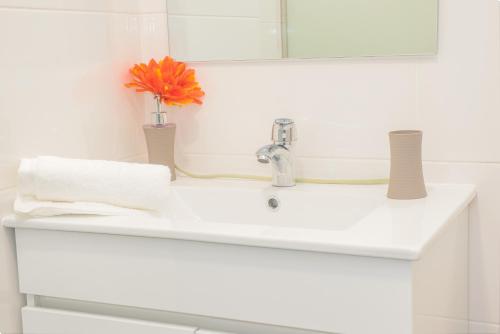 a bathroom sink with a flower in a vase on it at Arcadas Cozy Apartments - AU in Funchal