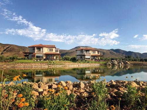 a couple of houses sitting next to a lake at El Cielo Resort in Valle de Guadalupe