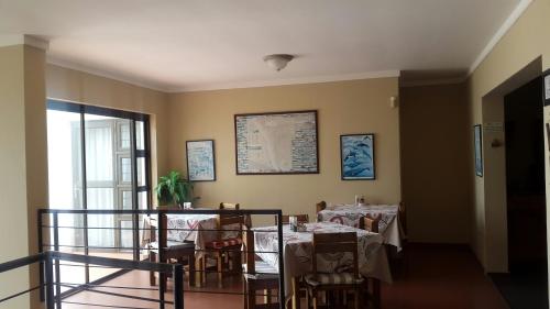 una sala da pranzo con tavoli, sedie e una finestra di Kleines Nest Bed and Breakfast a Walvis Bay