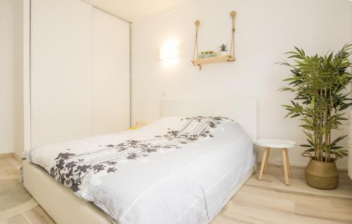 a white bedroom with a bed and a plant at "COSY" Appartement confort de 50m2 à 150m de la Mer et du Centre ville, parking gratuit in Canet-en-Roussillon