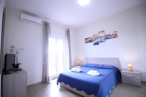 a bedroom with a blue bed and a window at Anagnina Apartment in La Romanina