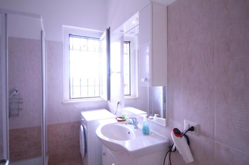 a white bathroom with a sink and a window at Anagnina Apartment in La Romanina