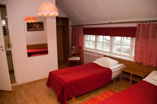 um quarto com 2 camas e um cobertor vermelho em Repo Hotel em Kuressaare