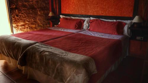 a bedroom with a large bed with red sheets and pillows at Posada Puerta Grande in Candelario