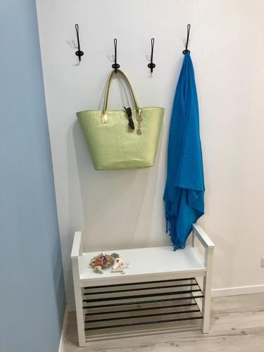 a white bench with a green purse on a wall at AzzurRomare Flat apartment in Lido di Ostia