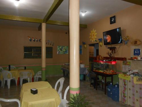 a room with a dining area with a column and a tv at Pousada Salmo 23 in Algodoal