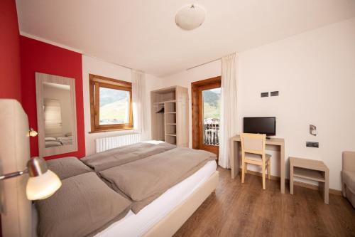 1 dormitorio con 1 cama y escritorio con TV en Baita Belvedere - Appartamenti Abar, en Livigno
