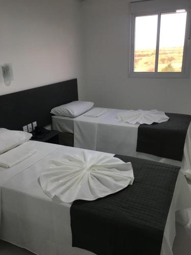 three beds in a room with a window at Hotel Oásis de Patos in Patos
