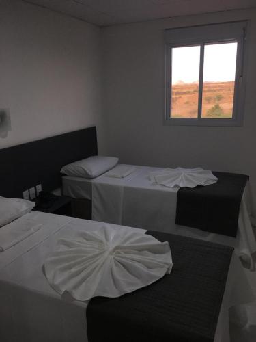 two beds in a room with a window at Hotel Oásis de Patos in Patos