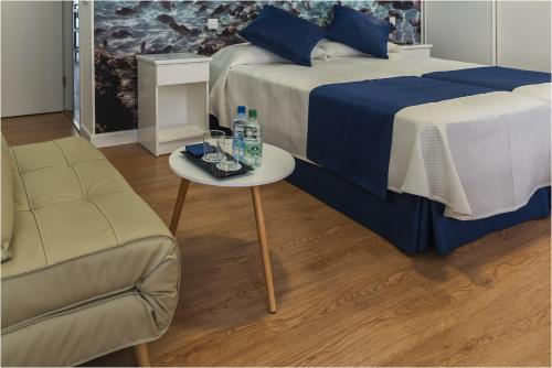 a bedroom with two beds and a table and a chair at Hotel Ciudad del Mar in Las Palmas de Gran Canaria
