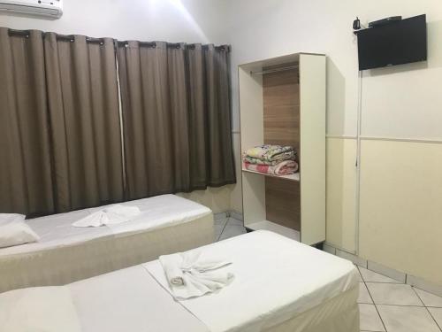 a hotel room with two beds and a television at Hotel central campo grande in Campo Grande