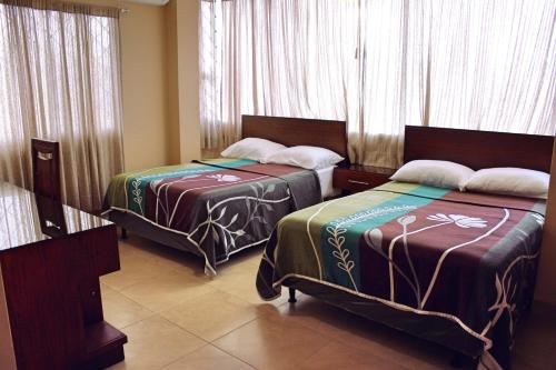 two beds in a room with windows and curtains at Maluva in Salinas