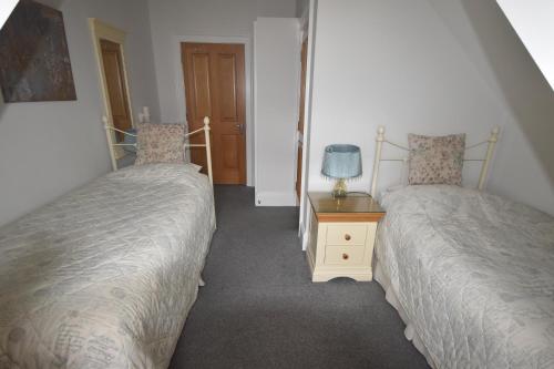 a bedroom with two beds and a table with a lamp at Gordon House in Wimborne Minster