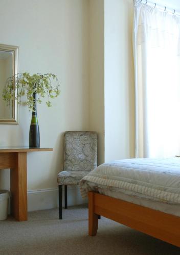 a bedroom with a bed and a chair and a table at Gordon House in Wimborne Minster