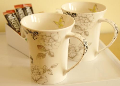 two cups sitting on a shelf with butterflies on them at Gordon House in Wimborne Minster