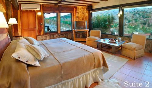 a bedroom with a large bed and a living room at Suites de la Colina in La Cumbrecita