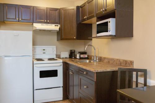 a kitchen with wooden cabinets and white appliances at Super 8 by Wyndham Fort McMurray in Fort McMurray