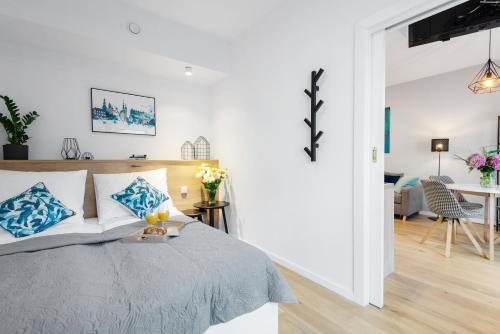 Un dormitorio blanco con una cama con almohadas azules. en Kopernika8 Miro Apartment with Balcony and AC, en Cracovia