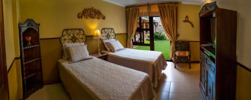 a hotel room with two beds and a television at Hostal Villa Toscana in Guatemala