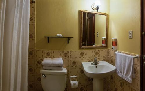 a bathroom with a sink and a toilet and a mirror at Hostal Villa Toscana in Guatemala
