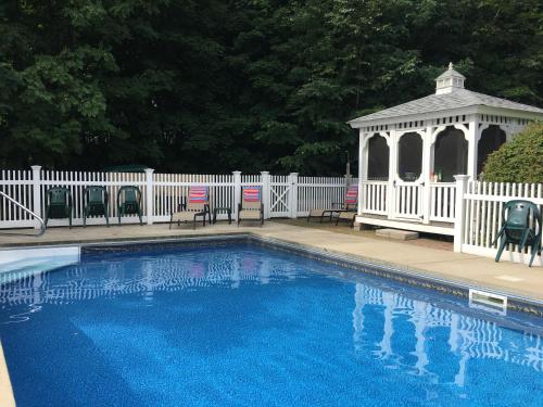 a swimming pool with a gazebo next to a white fence at Center Harbor Sutton House B & B in Center Harbor