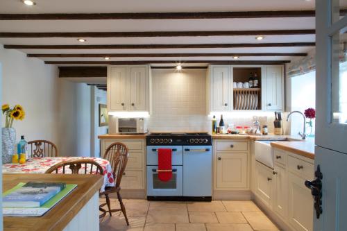 a kitchen with white cabinets and a stove top oven at Strawberry Cottage in Cheddar