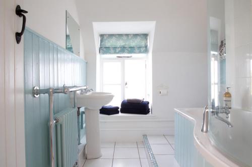 baño con lavabo, bañera y ventana en Strawberry Cottage en Cheddar