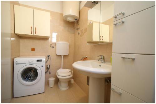 ein kleines Bad mit einer Waschmaschine und einem Waschbecken in der Unterkunft Apartment Slavko in Primošten