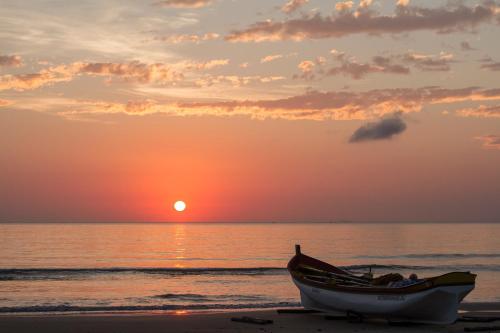 a boat sitting on the beach at sunset at Pousada Lugar ao Sol in Bombinhas