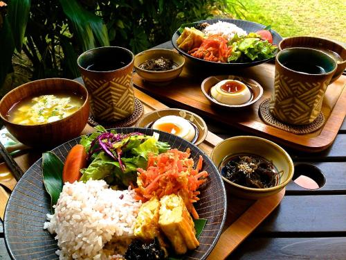 恩納的住宿－Akachichi Guesthouse，餐桌,上面有一盘饭和蔬菜