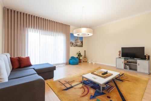 a living room with a blue couch and a table at Feel at home - Free private parking in Braga