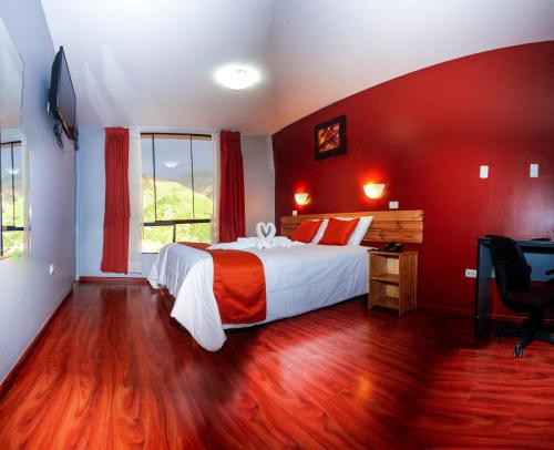 a bedroom with a bed with red walls and a desk at El Peregrino Apart Hotel in Abancay