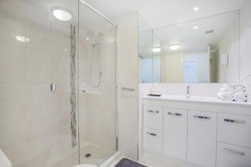 a white bathroom with a shower and a sink at Broadbeach in Gold Coast