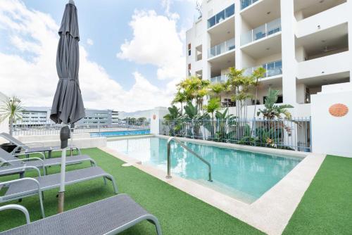 a swimming pool with chairs and an umbrella next to a building at Cairns City Apartments in Cairns