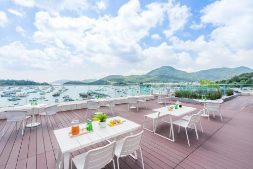 a deck with tables and chairs and a view of the water at The Pier Hotel in Hong Kong